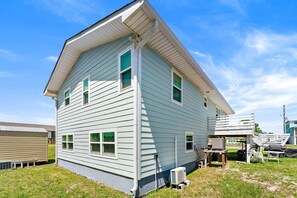Ein zweistöckiges Haus mit Satteldach, einer Veranda und einer kleinen angebauten Garage.