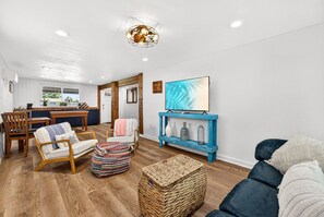 Ein modernes Wohnzimmer mit einer Couch, Sesseln, einem Couchtisch und einem blauen Regal mit einem Fernseher.