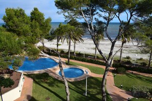 A pool surrounded by trees, a beach, and a clear view of the ocean. - At2202 in Denia With 2 Bedrooms and 2 Bathrooms (Denia)