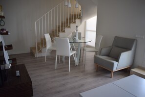 A modern living room with a staircase, a glass table, and a grey armchair. - At2202 in Denia With 2 Bedrooms and 2 Bathrooms (Denia)