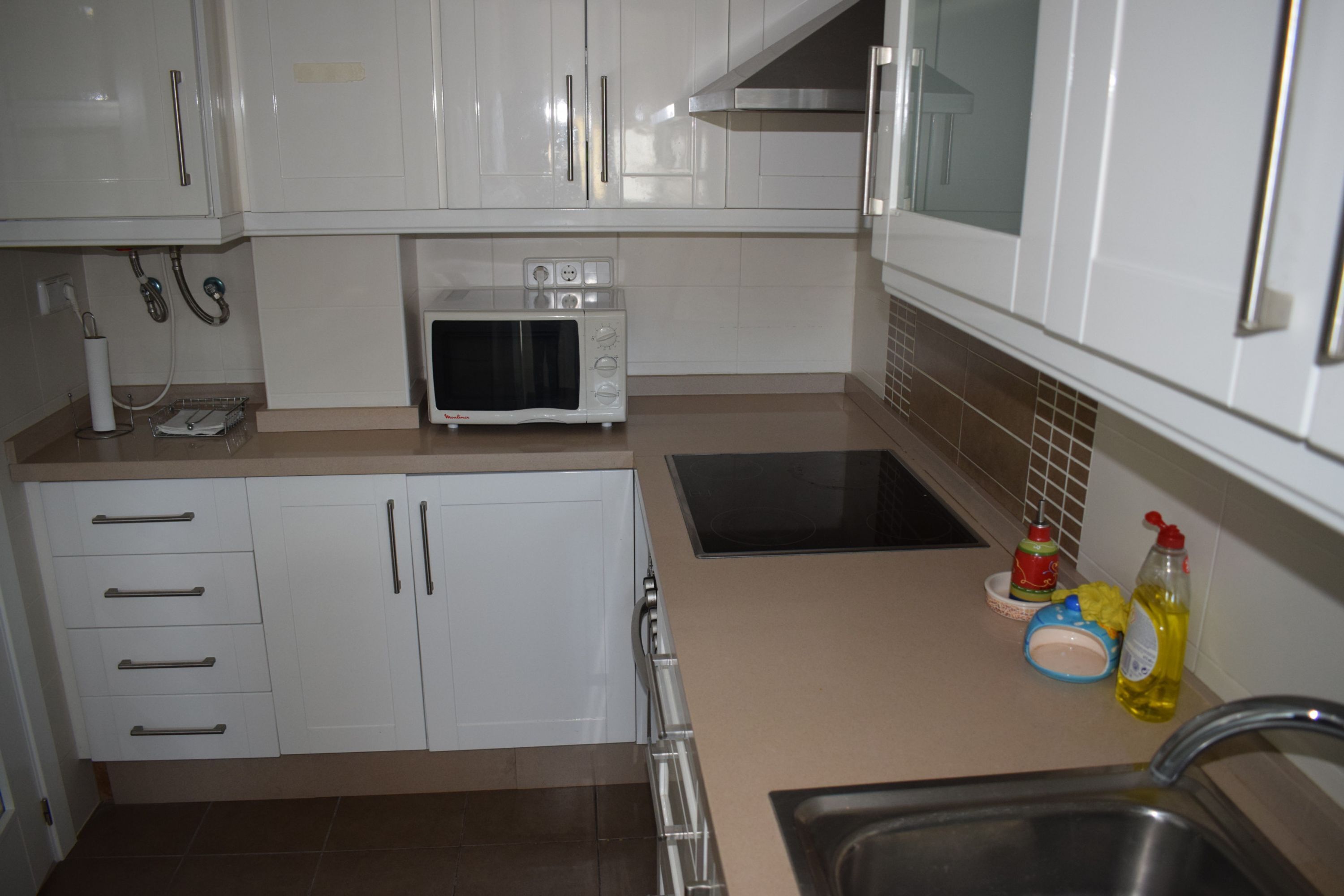 A kitchen with white cabinets, a microwave, a stove, and a sink.