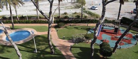 Un área de piscina con un sendero, palmeras y vistas a la playa y al océano.