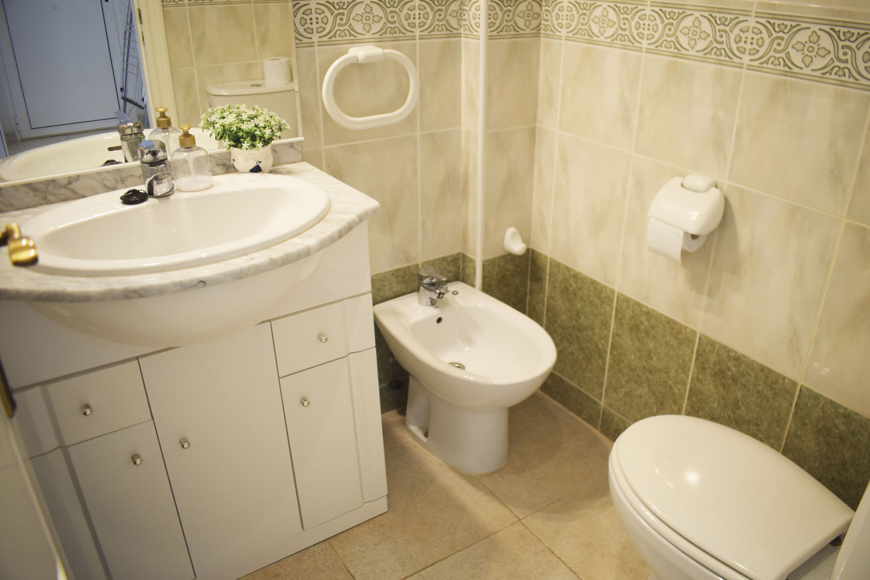 A bathroom with a sink, bidet, toilet, and a mirror.