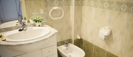 A bathroom with a sink, bidet, toilet, and a mirror.