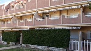 A multi-story building with balconies, a white fence, and a well-maintained hedge. - Pb3201 in Denia With 3 Bedrooms and 2 Bathrooms (Denia)