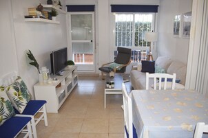 Una sala compacta con televisor, zona de estar y un balcón con vistas.