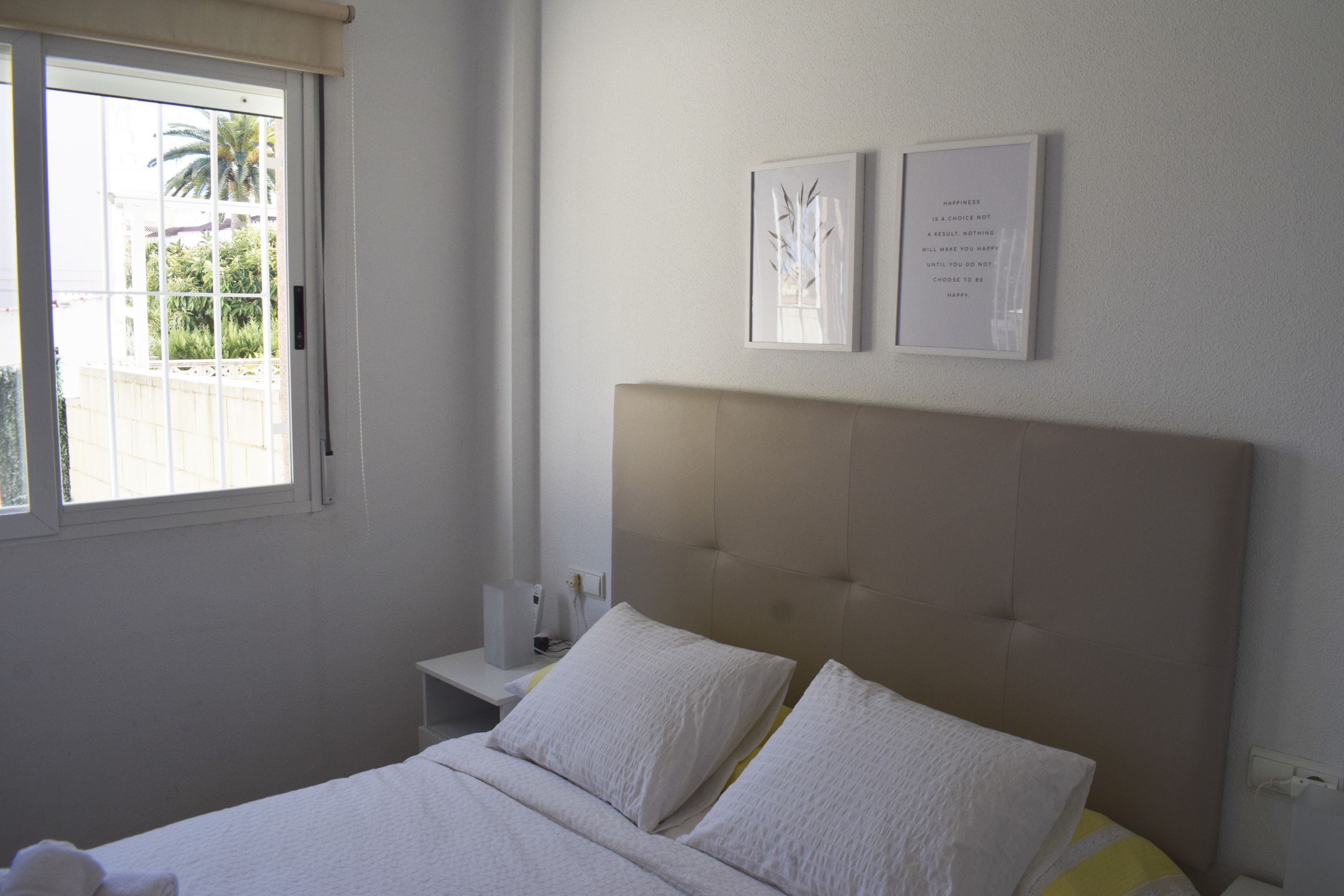 A bedroom with a bed, a bedside table, and two wall-mounted pictures.