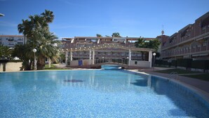 A swimming pool with a clear blue water surface, surrounded by a building with multiple balconies and a covered walkway. - Pb3201 in Denia With 3 Bedrooms and 2 Bathrooms (Denia)