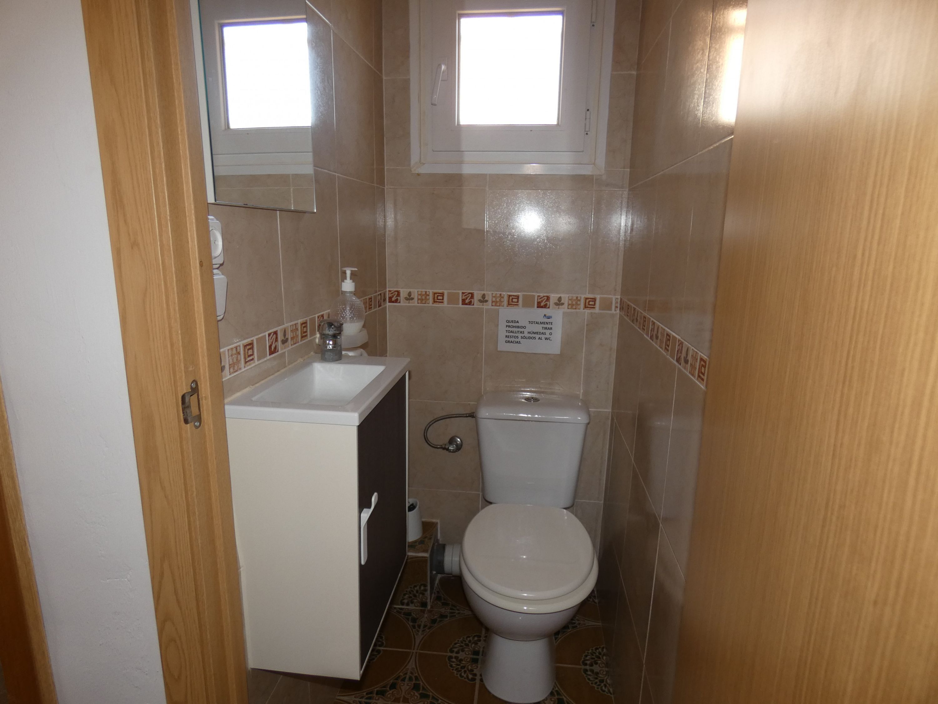 Ein kleines Badezimmer mit Toilette, Waschbecken und Spiegel.