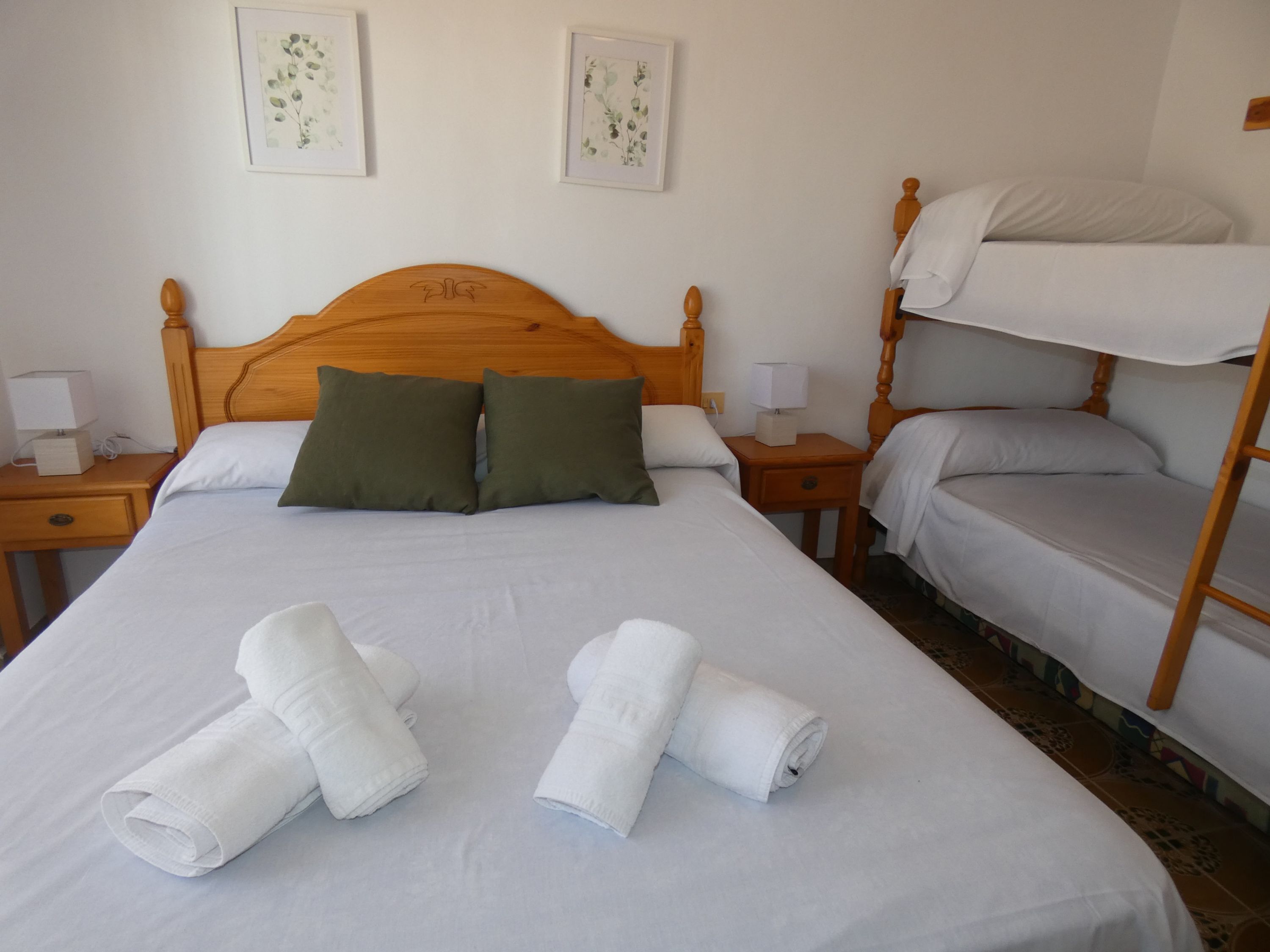 Une chambre d’hôtel avec un lit simple, deux oreillers, une table de chevet avec une lampe et un lit superposé.