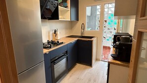 Eine kompakte Küche mit Kühlschrank, Backofen, Spüle und einer Kaffeemaschine.