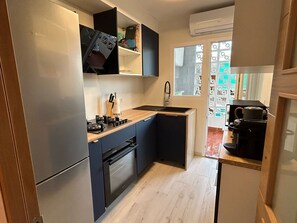 Eine kompakte Küche mit Kühlschrank, Backofen, Spüle und einer Kaffeemaschine.