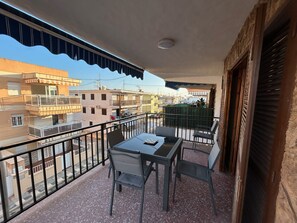 A balcony with a table and chairs, a view of neighboring buildings, and a closed shutter on the right. - Ap602 in Oliva With 3 Bedrooms and 1 Bathrooms (Oliva)