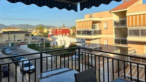 Ein Balkon mit Blick auf eine Straße, Gebäude und Berge.
