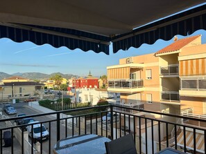 Ein Balkon mit Blick auf eine Straße, Gebäude und Berge.