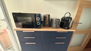 Eine Küchenzeile mit Mikrowelle, Toaster und Kaffeemaschine auf einer Holzausziehtafel.