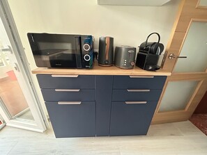 Eine Küchenzeile mit Mikrowelle, Toaster und Kaffeemaschine auf einer Holzausziehtafel.