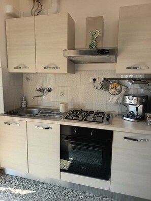 A modern kitchen with a gas stove, oven, and a coffee machine. - Vada Apartment - VadaLi (Vada)