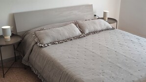 A bedroom with a bed, two bedside tables, and two wall-mounted lamps. - Vada Apartment - VadaLi (Vada)