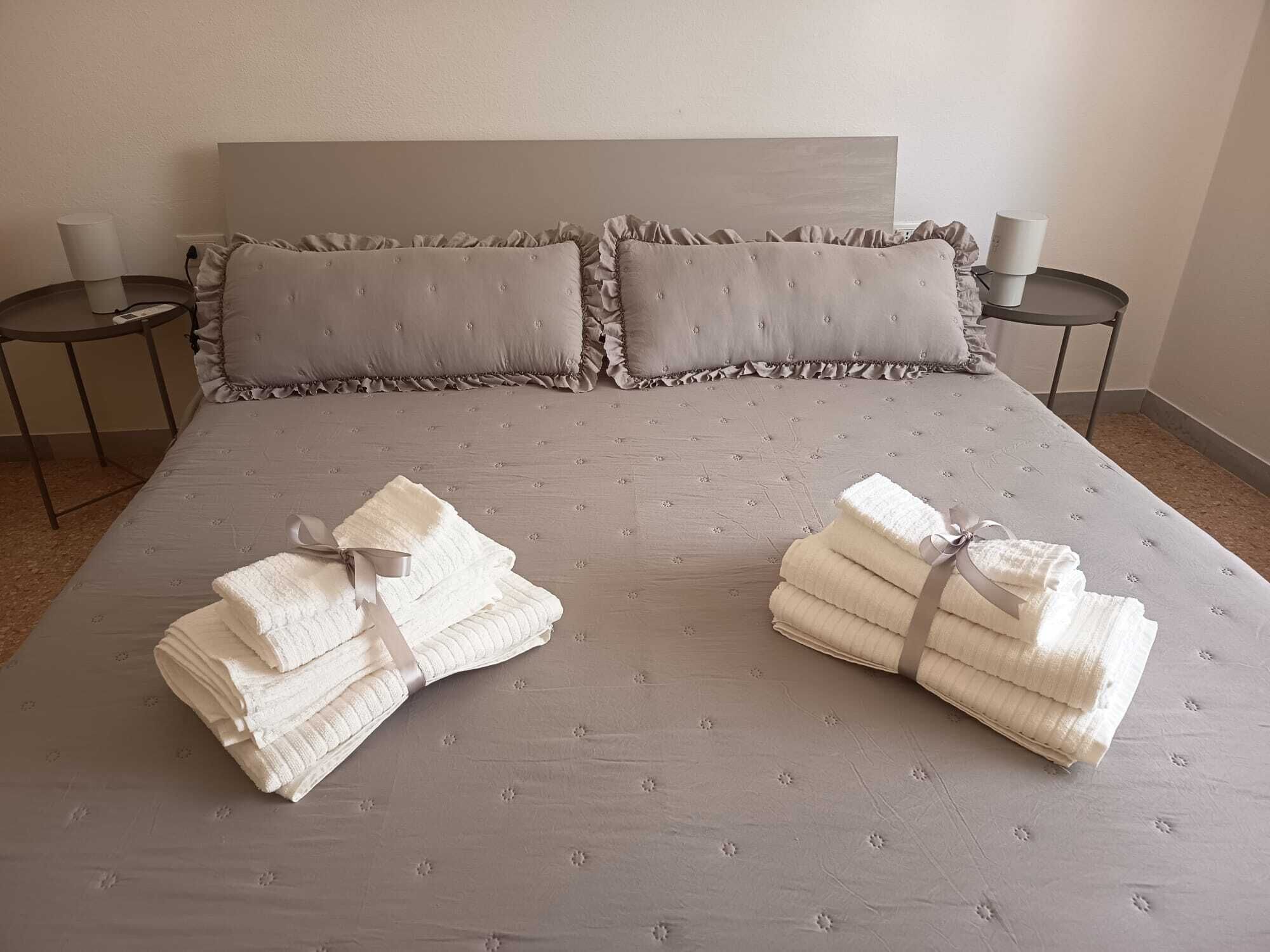 A neatly made bed with pillows and folded towels on a textured bedspread.