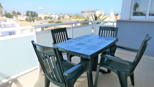 A balcony with a table and chairs, a view of buildings, and a clear sky. - Ap204 in Oliva With 2 Bedrooms and 1 Bathrooms (Oliva)