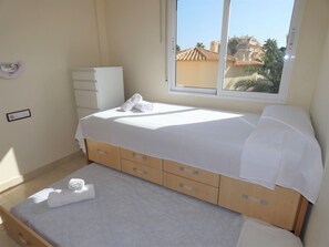 Un dormitorio con una cama, una ventana, un aparador y un interruptor de luz en la pared.