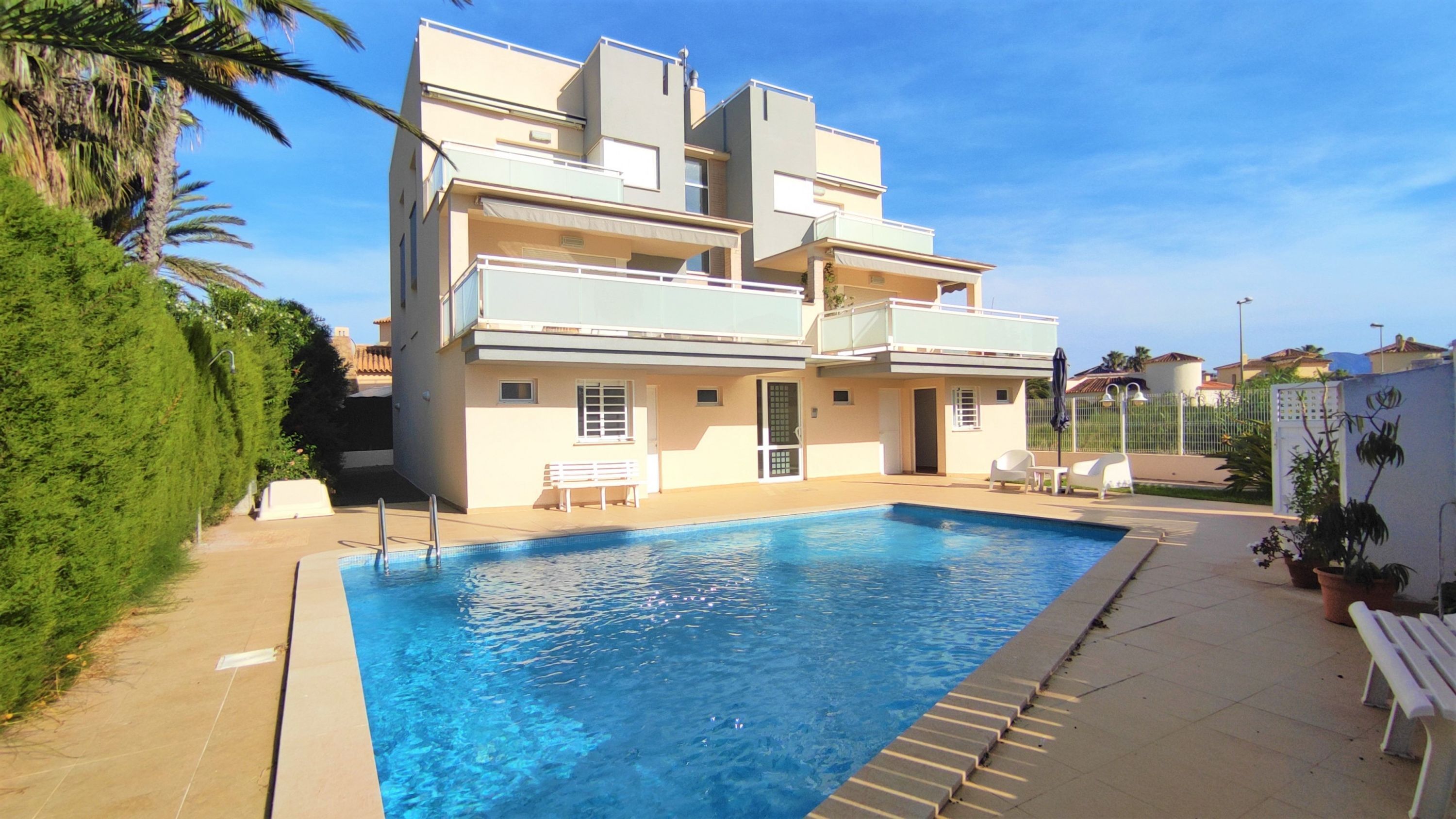 Un edificio moderno de varios pisos con piscina, mobiliario exterior y un jardín bien cuidado.
