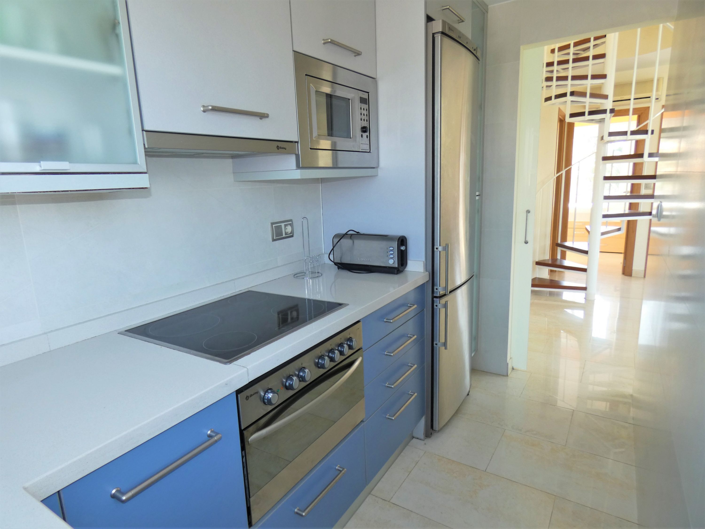 Eine moderne Küche mit integriertem Mikrowellenherd, Toaster und einem Edelstahlkühlschrank.