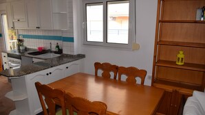 Eine Küche mit einem Holztisch, Stühlen, einem eingebauten Backofen und einem Fenster.