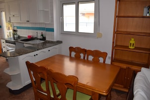 Una cocina con una mesa de madera, sillas, horno empotrado y una ventana.