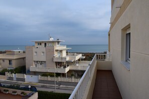 Ein Wohngebäude mit Balkon, das auf eine Straße und ein Gewässer blickt.