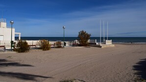 Ein Strand mit einem weißen Gebäude, einem Zaun und Straßenlaternen.
