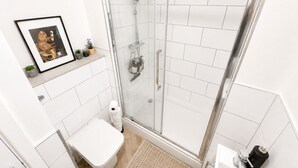 A modern bathroom with a glass shower enclosure, a toilet, a sink, and a framed picture on the wall. - Free Parking | Homely Gloucester Rd Flat Sleeps 3 (Bristol)