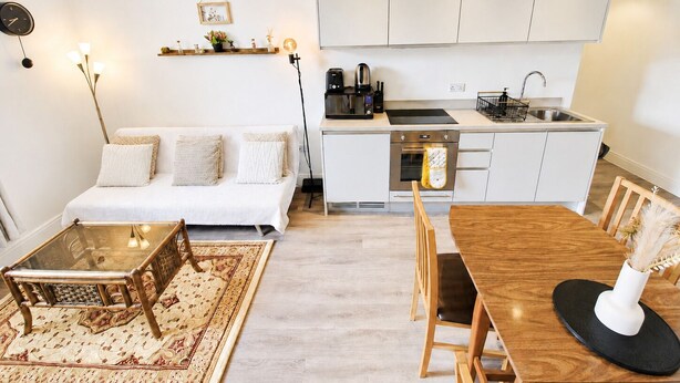 Um espaço compacto com cozinha compacta, um sofá, uma mesa de jantar e uma máquina de café.