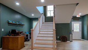 A spacious room with a wooden staircase, a desk with a computer, and a window with curtains. - The Lazy Tiger Hostel (Asheville)