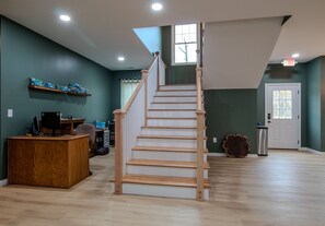 Una habitación amplia con una escalera de madera, un escritorio con computadora y una ventana con cortinas.