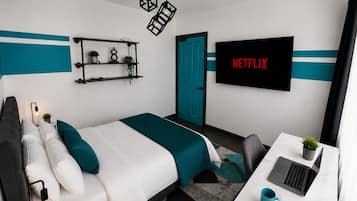A modern bedroom with a bed, desk, TV, and decorative items.