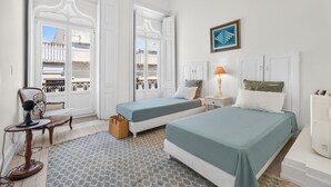 A hotel room with two beds, a chair, a lamp, a wicker basket, and a framed artwork on the wall. - Casa Estrela, a mansion in the heart of Olhão, (Olhão)