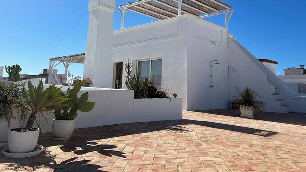 A modern white building with a flat roof, a covered outdoor area, and potted plants. - Casa Estrela, a mansion in the heart of Olhão, (Olhão)