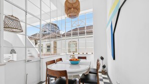 A dining area with a white table, black and white checkered floor, and a view of buildings through large windows. - Casa Estrela, a mansion in the heart of Olhão, (Olhão)