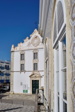 Un bâtiment historique aux détails architecturaux raffinés, doté d’une entrée fermée par un portail et surplombant un ciel d’un bleu éclatant.