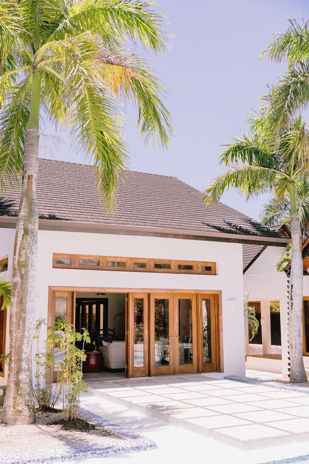A modern building with a tiled roof, large glass doors, and palm trees.