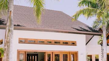 A modern building with a tiled roof, large glass doors, and palm trees.