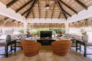 Un espacio habitable de concepto abierto con techo de paja, muebles de mimbre y chimenea.