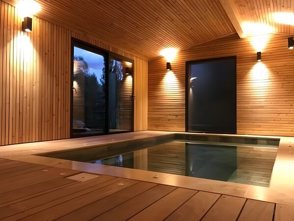 A wooden interior with a hot tub, wooden walls, and ceiling lights.