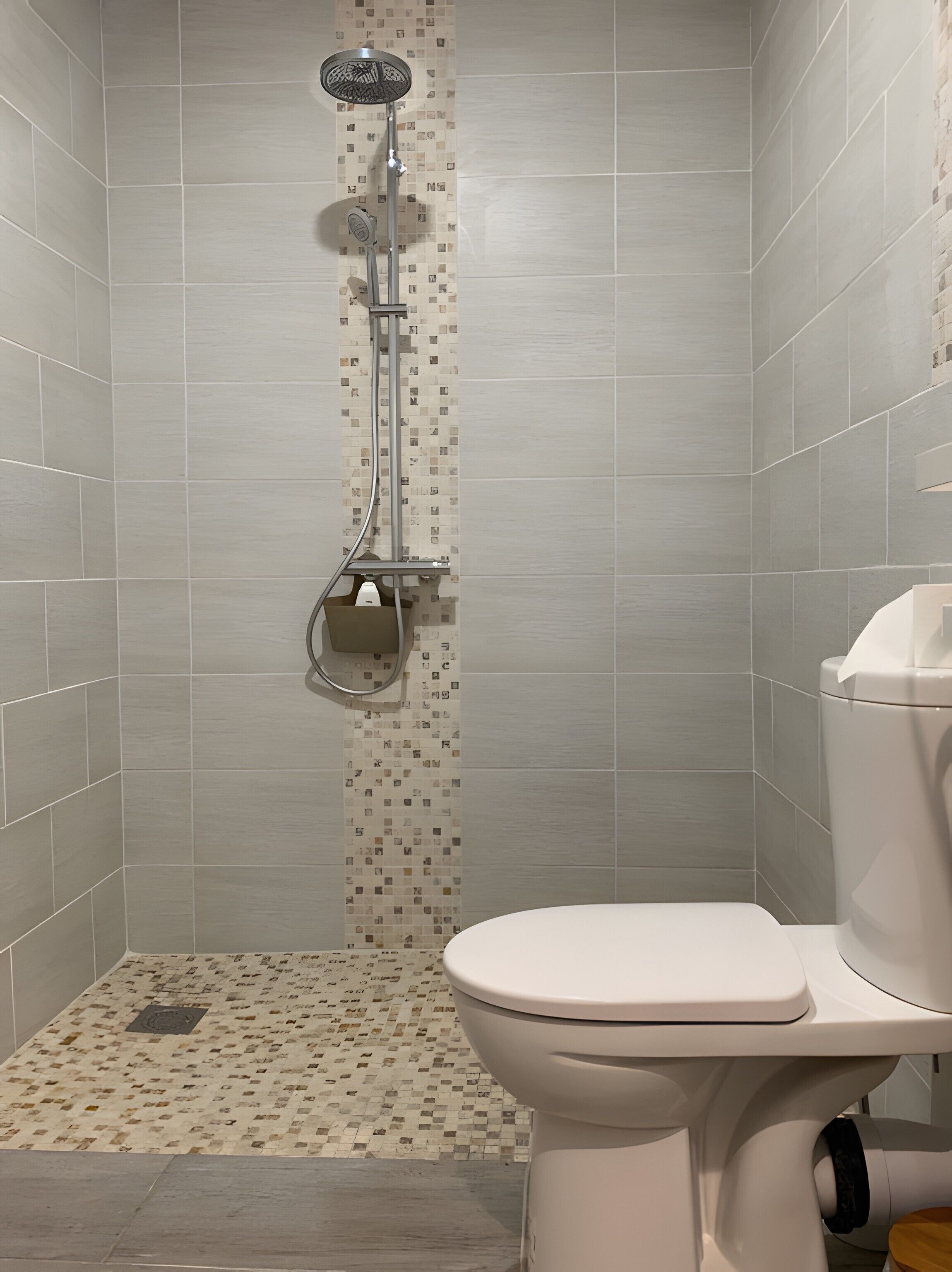 A bathroom with a shower, toilet, and a tiled floor.