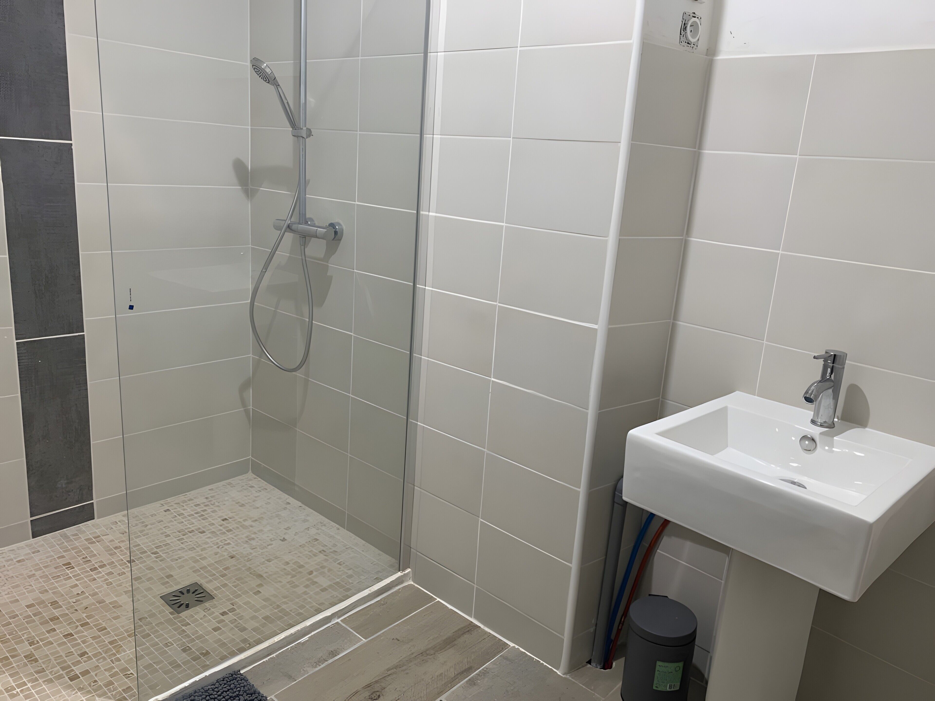 Une salle de bain avec douche, lavabo et murs carrelés.