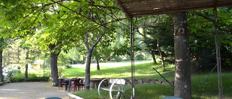 An outdoor seating area with tables and chairs, a covered section, and a vintage wagon wheel.