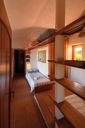 A narrow hallway with a bed at the end, wooden bunk beds on the right, and a door on the left. - Villa Portobello 10+2, Emma Villas (Portobello)