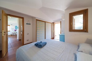 Um quarto com cama, janela, porta e vista para o exterior.